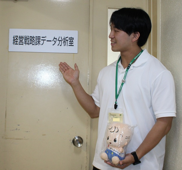 データ分析室前で立つ新規採用職員