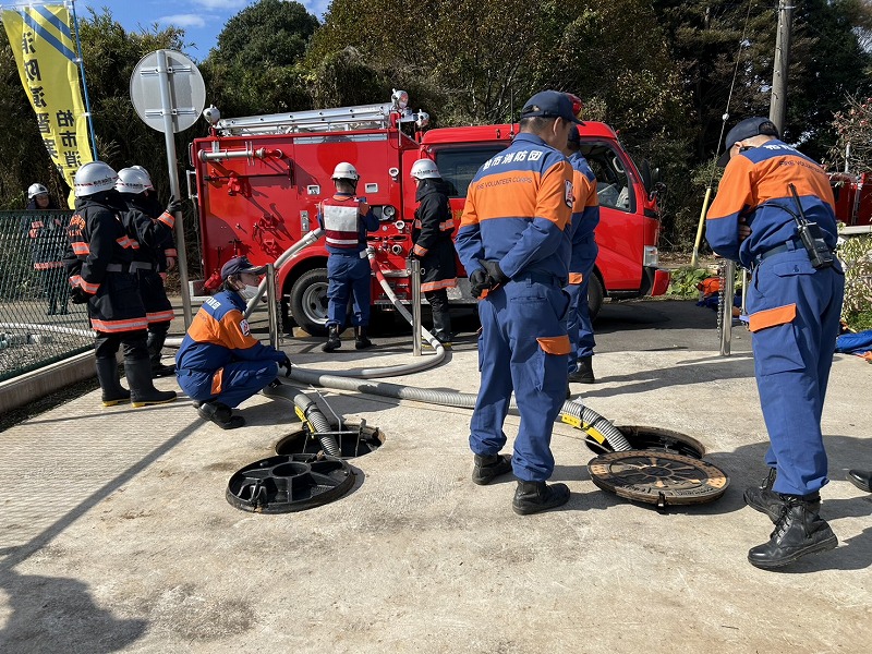 消防車両から吸管という水を吸い上げるホースを伸ばし、防火水槽から水を吸い上げている様子